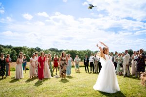 A bride trowing a wedding bouquet at Tanyard Farm in Dorset